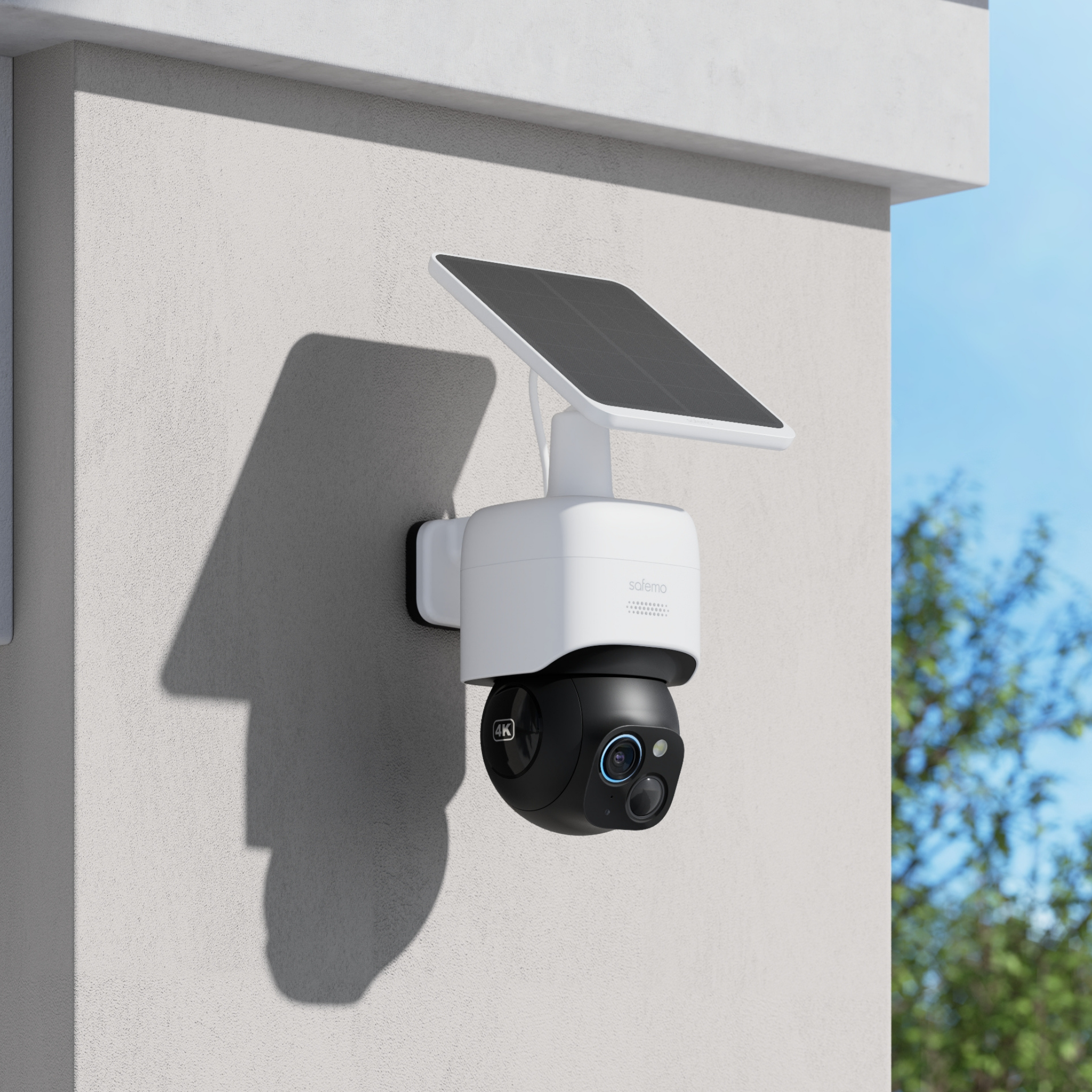 Produktfoto von 360 Grad Überwachungskamera mit integriertem Solarpanel in Profilansicht montiert an eine Hausfassade. Blauer Himmel und Baum in Unschärfe im Hintergrund.