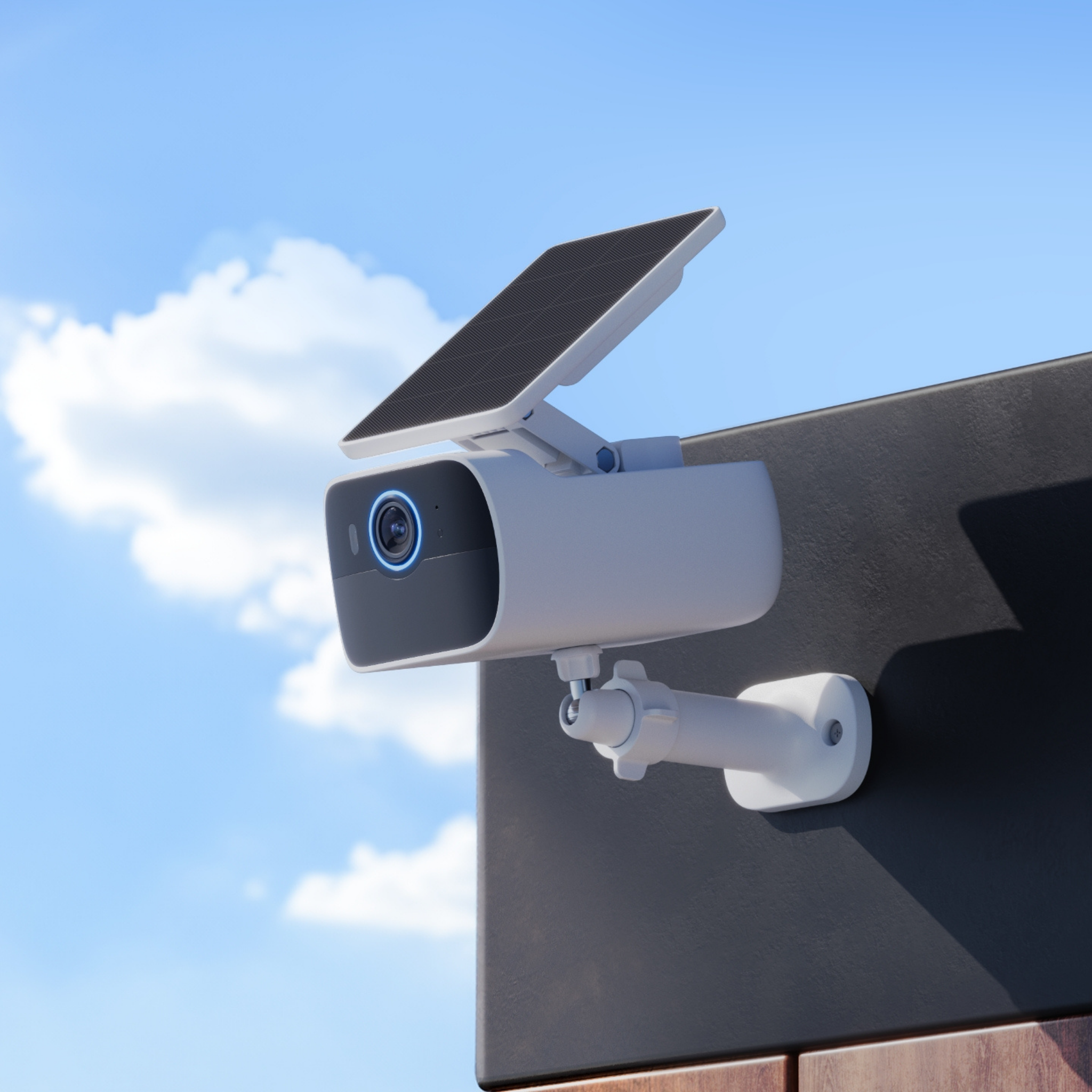 Produktfoto einer Überwachungskamera mit integriertem Solarpanel montiert an eine Gebäudefassade. Im Hintergrund blauer Himmel.