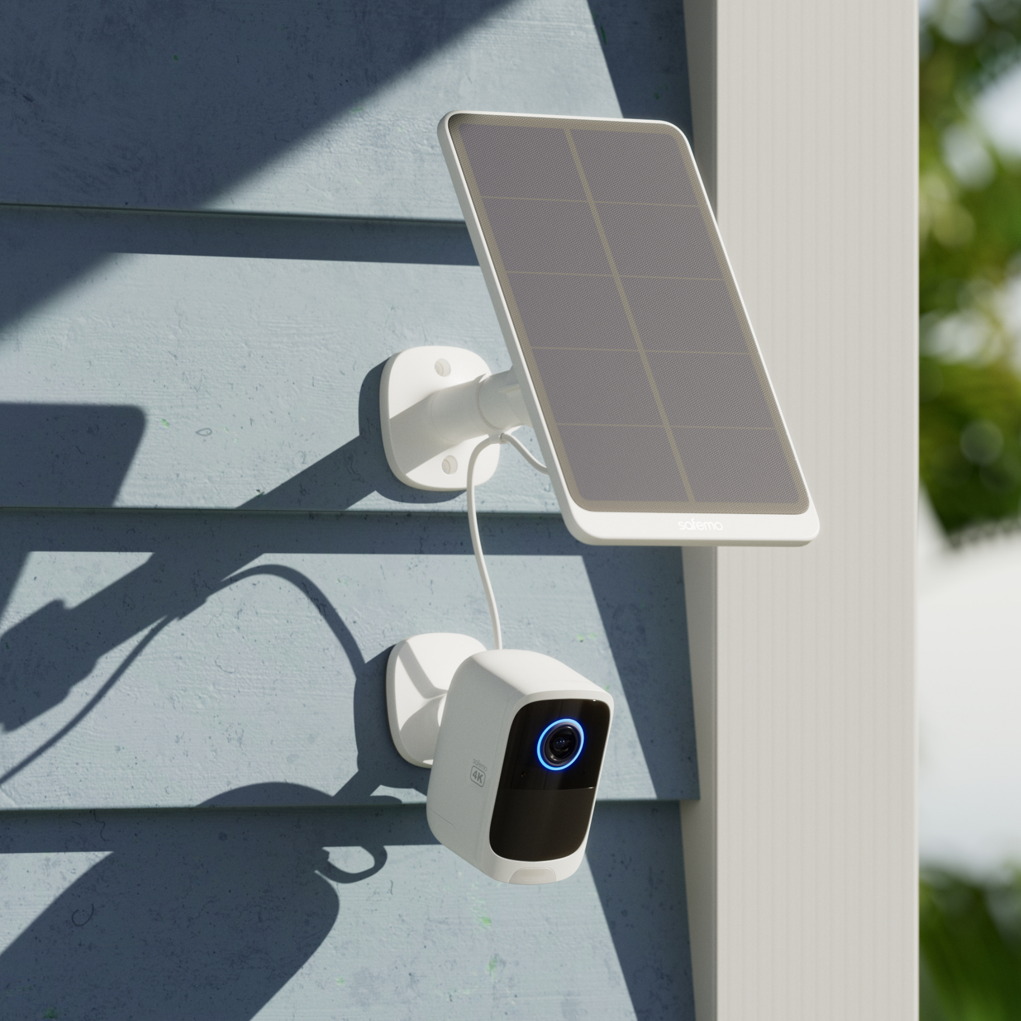 Produktfoto einer Überwachungskamera mit angeschlossenem Solarpanel darüber. Beide Komponenten sind an die Holzfassade eines Gebäudes montiert.