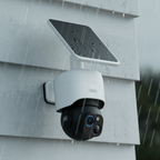 Produktfoto von 360 Grad Überwachungskamera mit integriertem Solarpanel in Profilansicht bei Regen. Montiert an Holzfassade. 